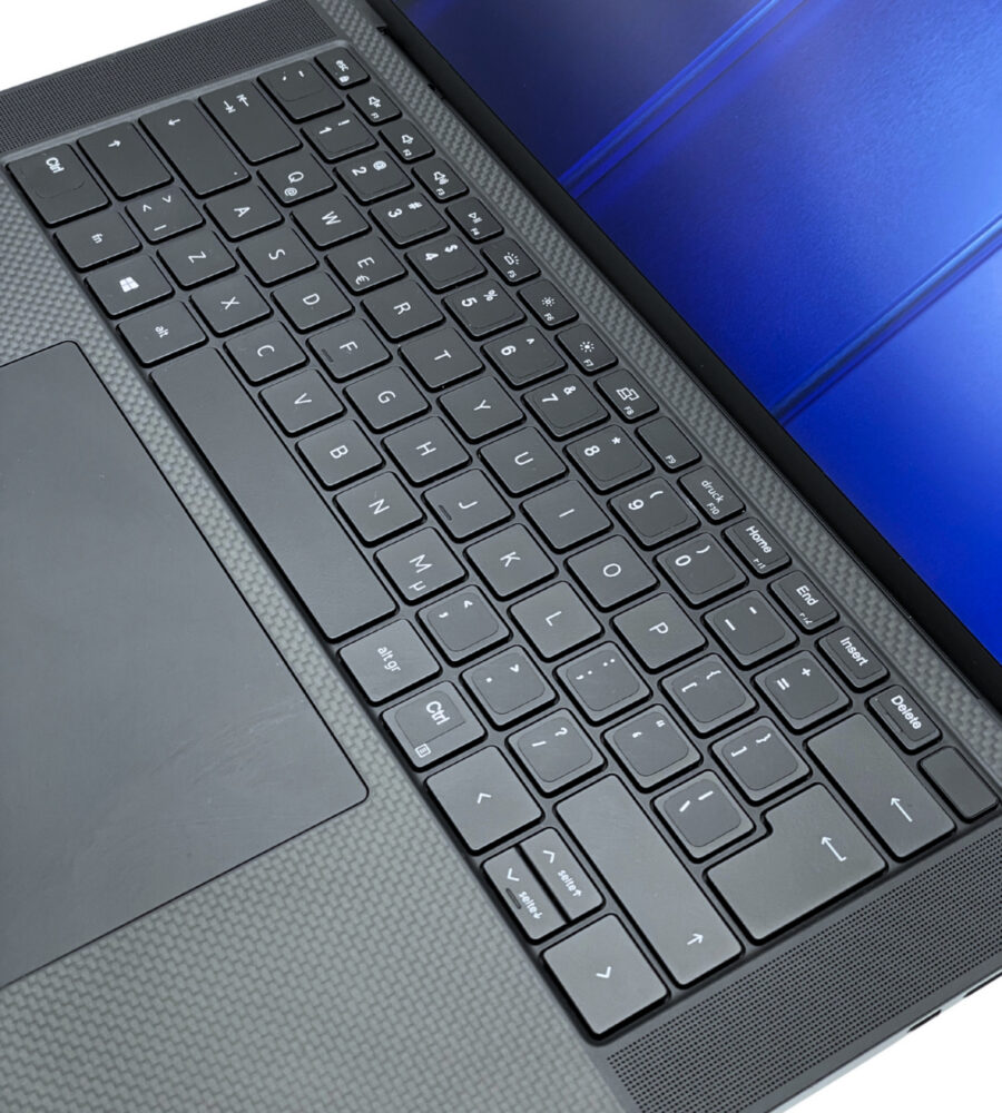 Dell Precision 5560 – układ klawiatury i touchpad Dell Precision 5560 zbliżenie na podświetlaną klawiaturę i duży touchpad karbonowy